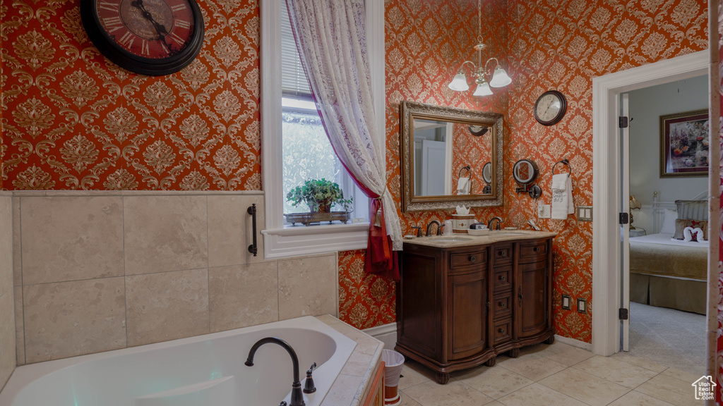 Bathroom featuring a notable chandelier, a washtub, vanity with extensive cabinet space, and tile floors