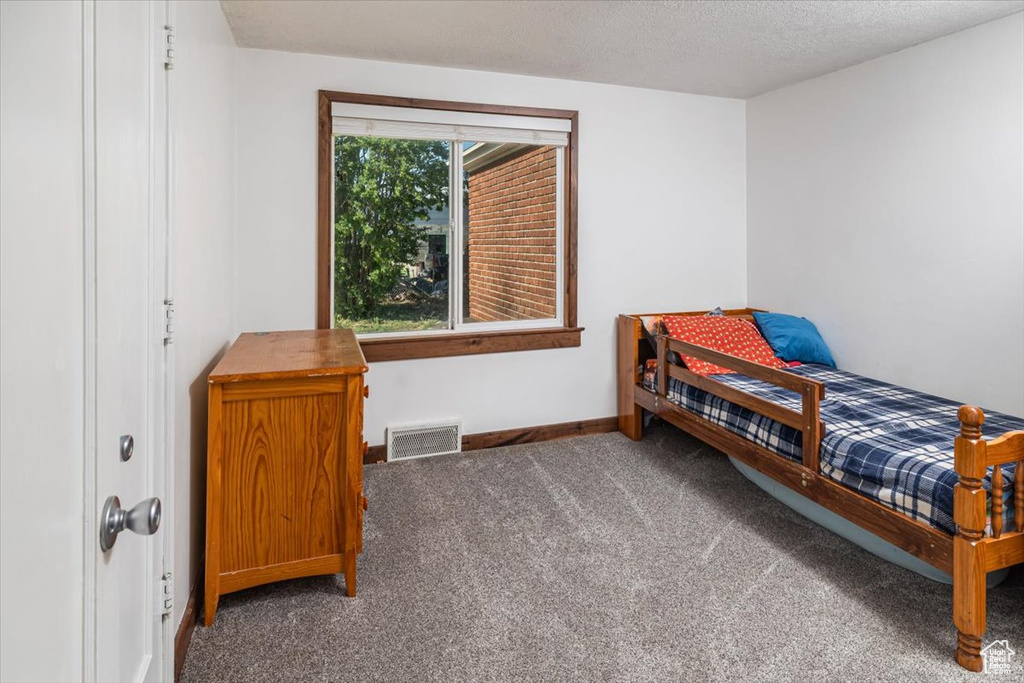 Bedroom with a textured ceiling and dark colored carpet