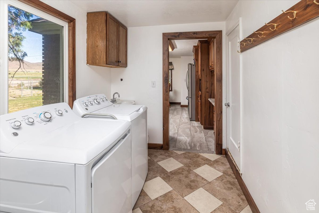 Laundry room with cabinets, sink, light tile flooring, and washer and clothes dryer