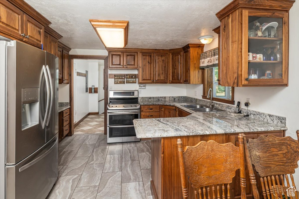 Kitchen featuring appliances with stainless steel finishes, sink, light tile floors, and kitchen peninsula