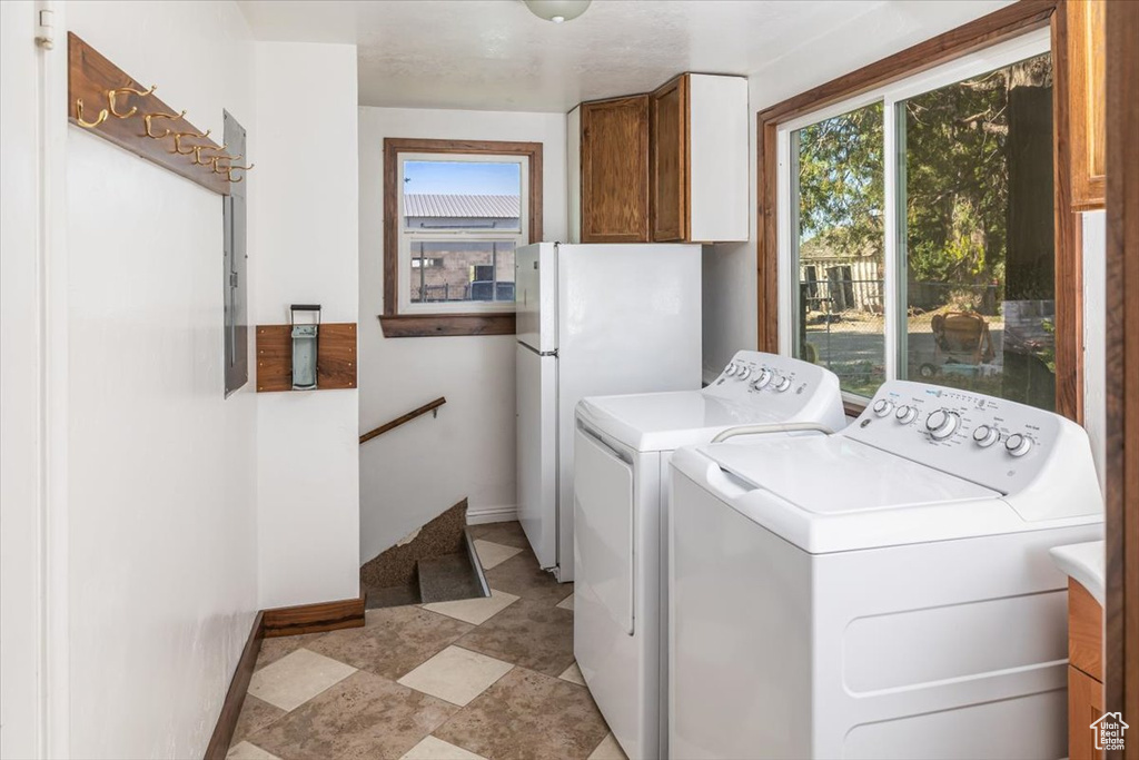 Clothes washing area featuring independent washer and dryer and light tile floors