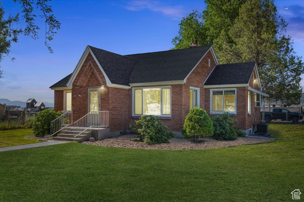 View of front of house featuring a lawn and central AC unit