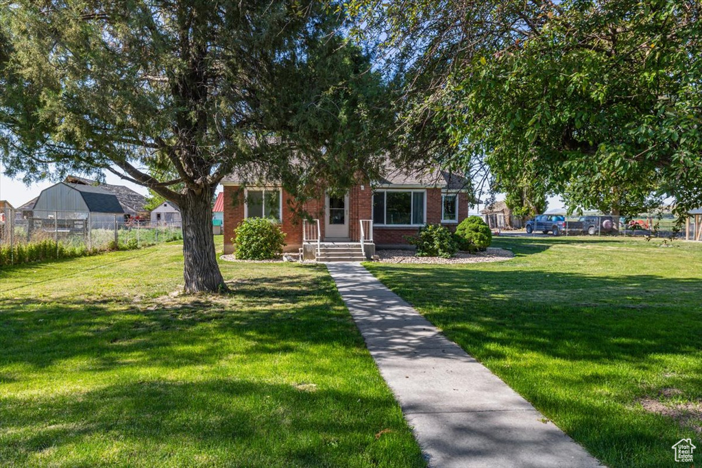 View of property hidden behind natural elements with a front yard