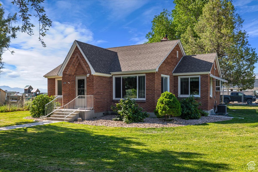 View of front of property with a front yard and central air condition unit