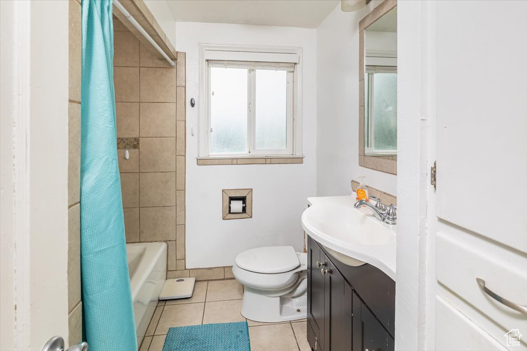 Full bathroom with tile floors, vanity, toilet, and shower / bathtub combination with curtain