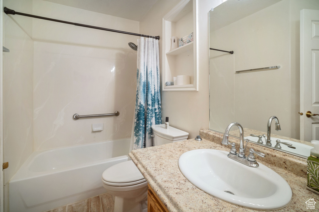 Full bathroom with wood-type flooring, shower / bath combo with shower curtain, toilet, and vanity