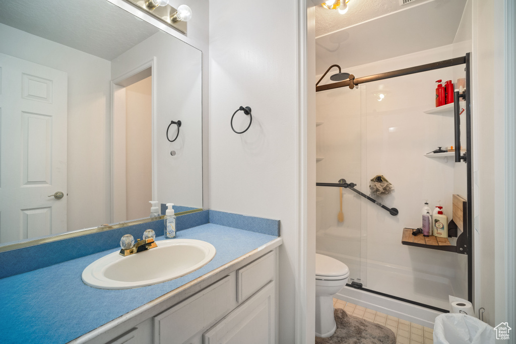 Bathroom with vanity with extensive cabinet space, an enclosed shower, toilet, and tile floors