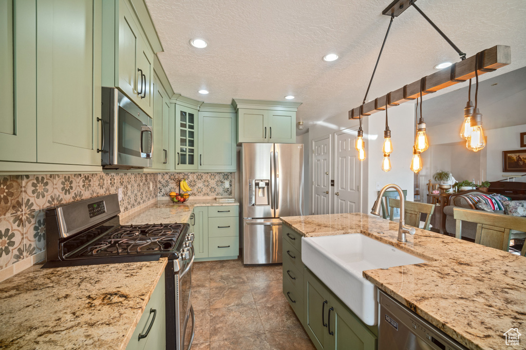 Kitchen featuring appliances with stainless steel finishes, decorative light fixtures, sink, and green cabinets