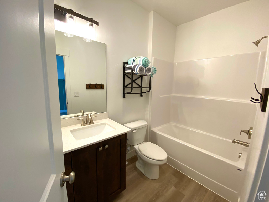 Full bathroom featuring toilet, vanity, bathing tub / shower combination, and hardwood / wood-style floors