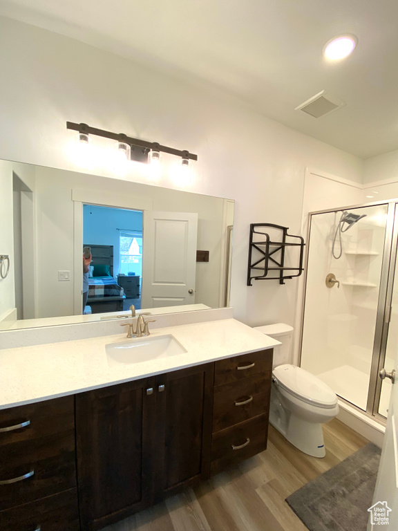 Bathroom with a shower with door, hardwood / wood-style flooring, vanity, and toilet