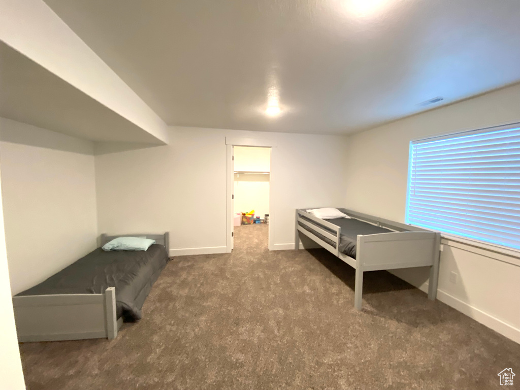 Unfurnished bedroom featuring a walk in closet and dark carpet