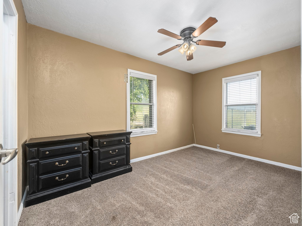 Carpeted empty room featuring plenty of natural light and ceiling fan