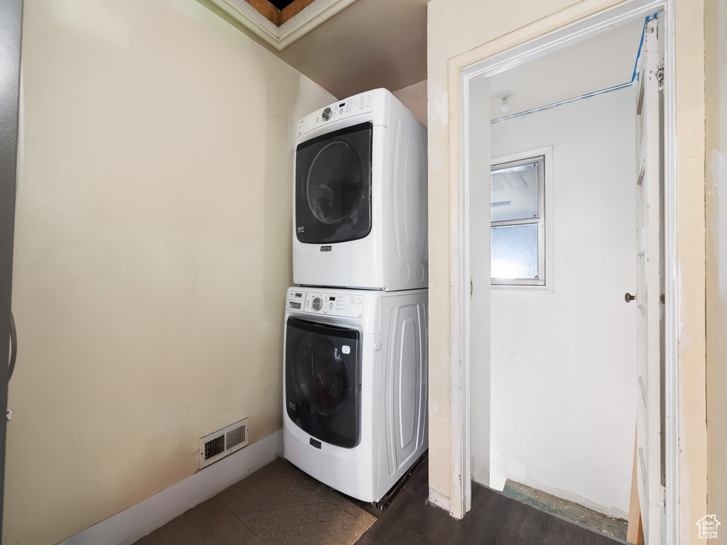 Washroom featuring stacked washer and dryer and dark hardwood / wood-style flooring