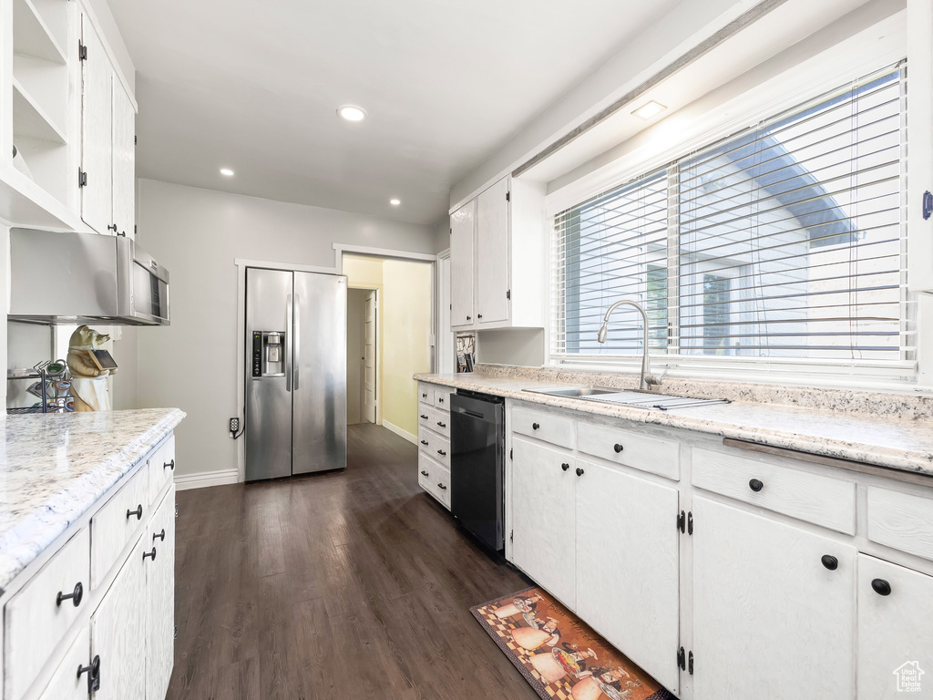 Kitchen featuring light stone counters, stainless steel appliances, dark wood-type flooring, white cabinets, and sink