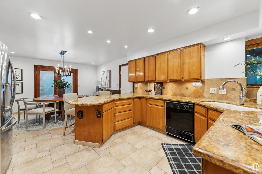 Kitchen with hanging light fixtures, sink, kitchen peninsula, tasteful backsplash, and black dishwasher