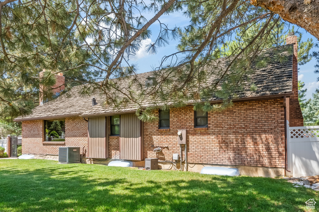 View of front of house with a front yard and central AC