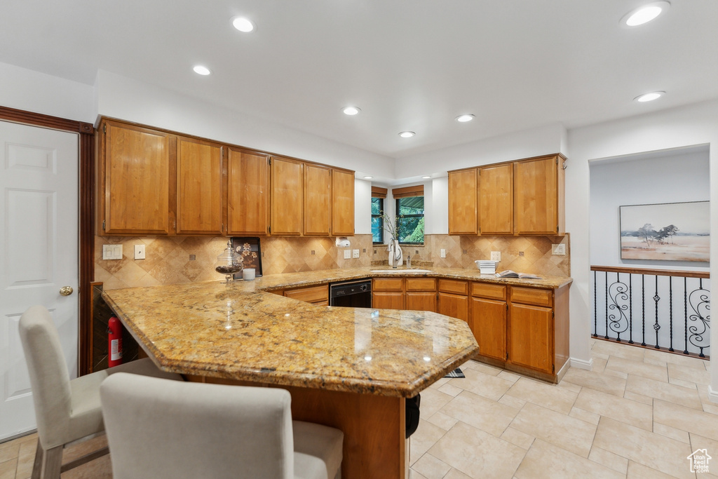 Kitchen with decorative backsplash, kitchen peninsula, a breakfast bar area, and sink