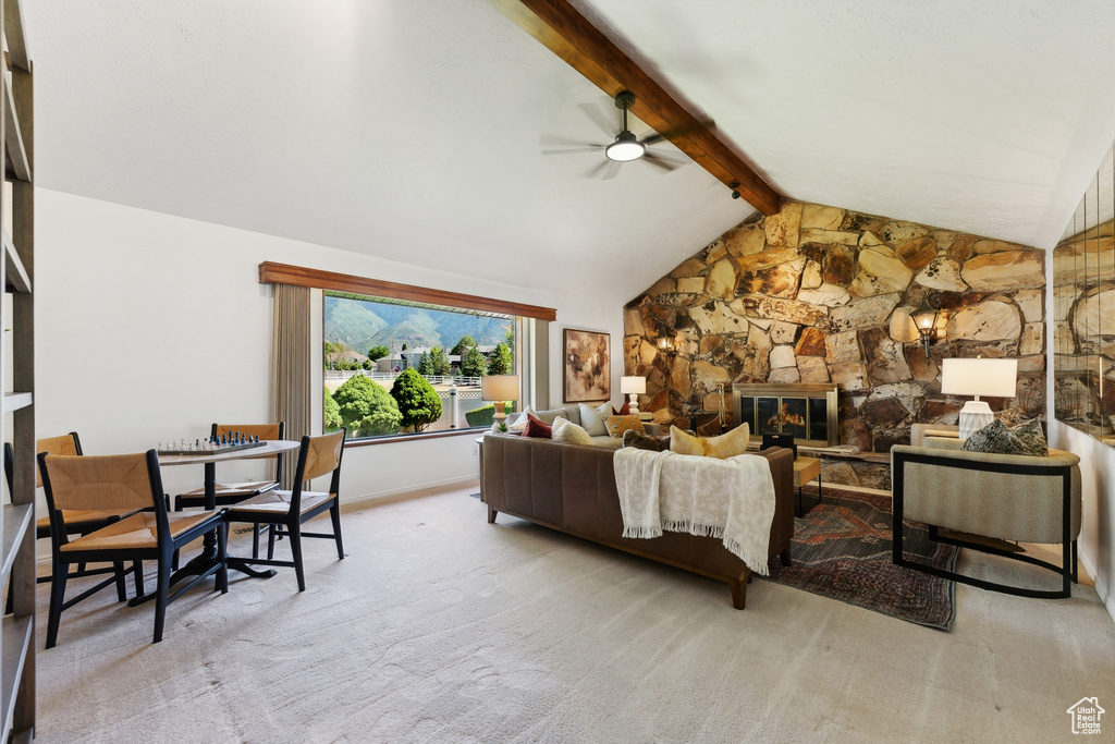 Living room featuring light carpet, ceiling fan, lofted ceiling with beams, and a fireplace