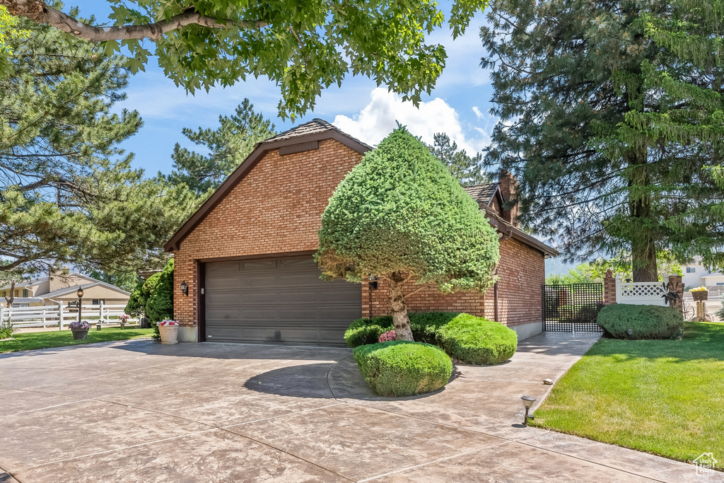 View of side of home featuring a lawn and a garage