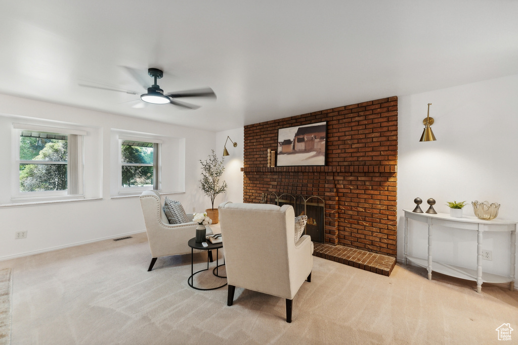 Living room with ceiling fan, a fireplace, and light carpet