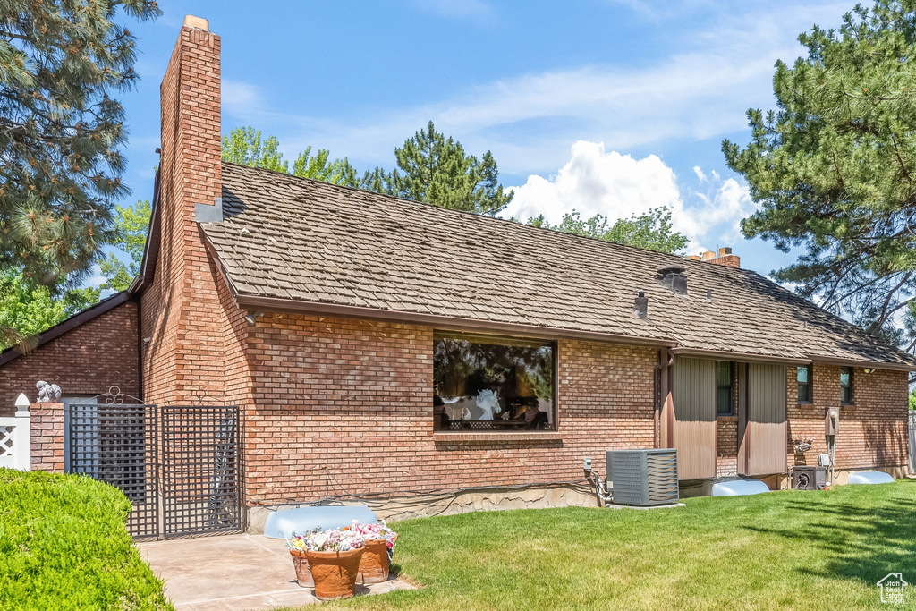 Rear view of property with a lawn, a patio, and central AC