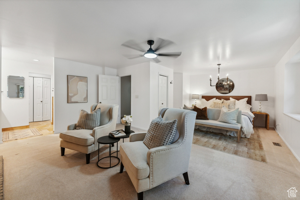 Carpeted bedroom with ceiling fan with notable chandelier