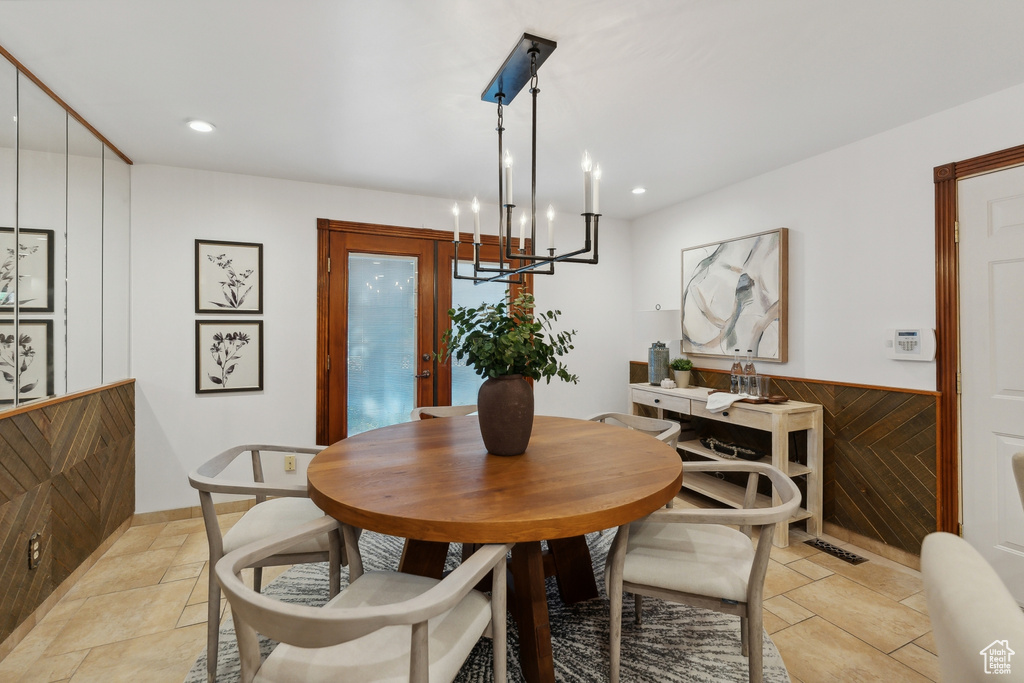 Dining space featuring wood walls and a chandelier