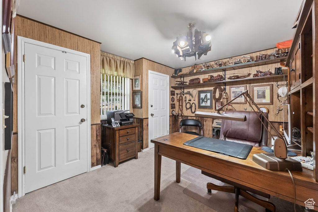 Carpeted home office with wood walls and an inviting chandelier