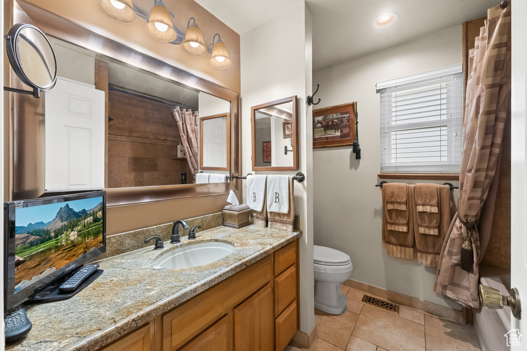 Bathroom with vanity, toilet, a shower with shower curtain, and tile patterned floors