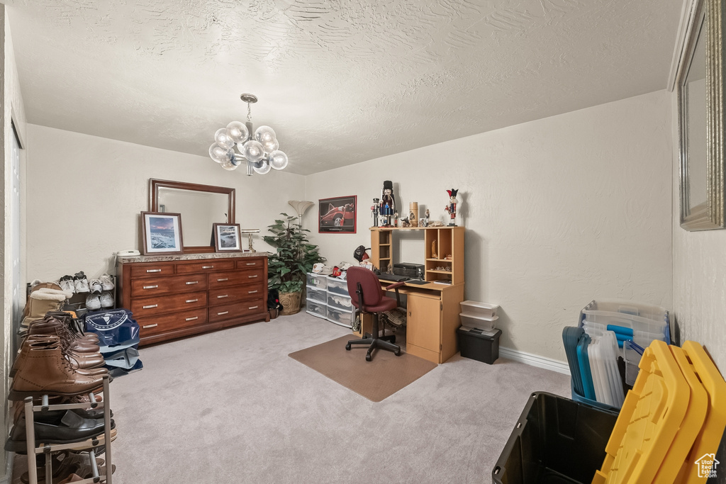 Carpeted office featuring a notable chandelier and a textured ceiling