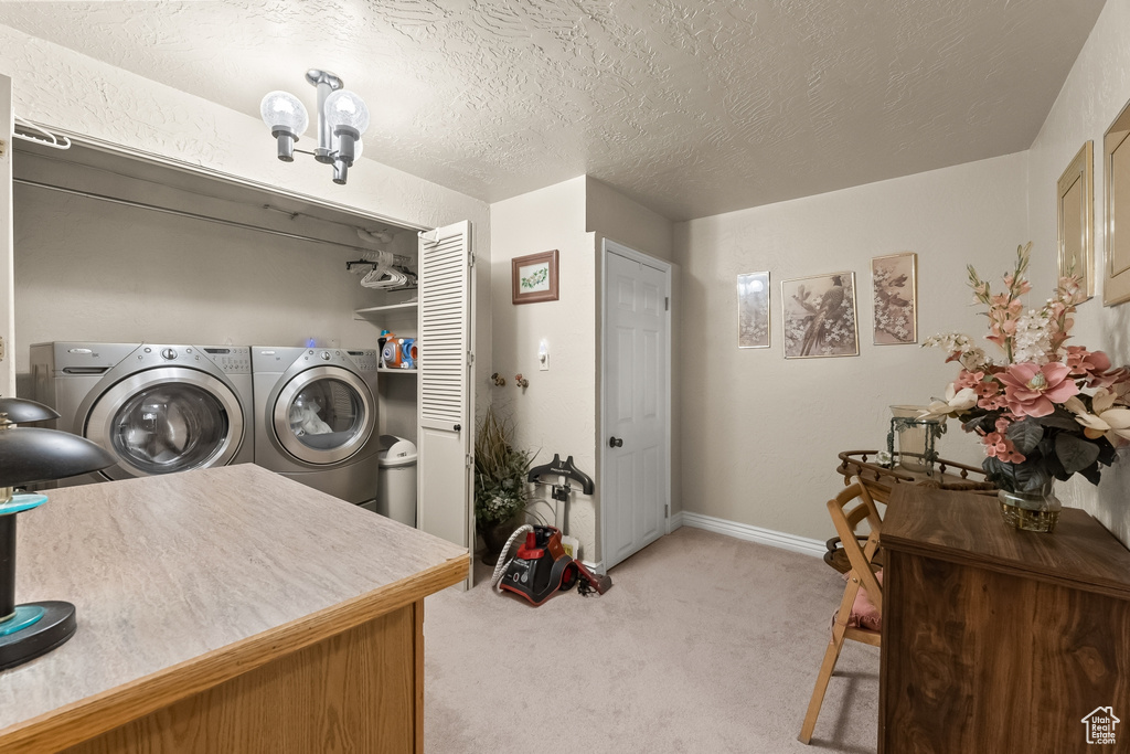 Washroom featuring a textured ceiling, light carpet, and washer and dryer