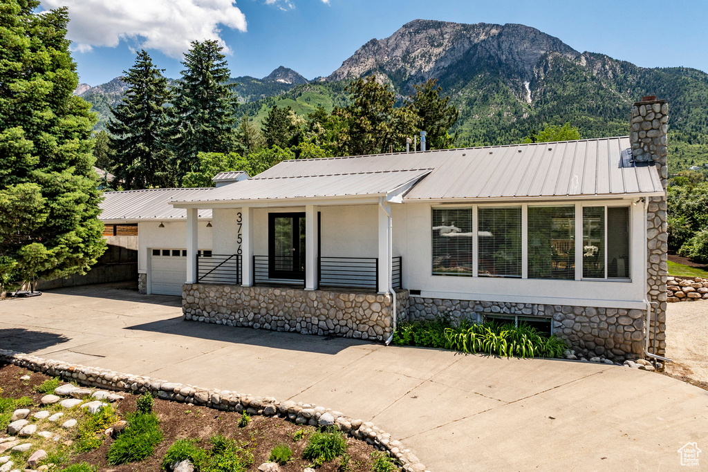 View of front facade with a garage, a mountain view, and covered porch