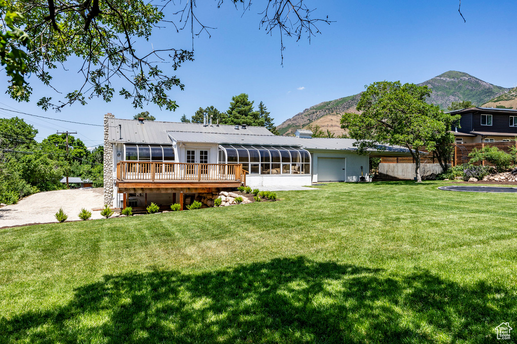 Rear view of house featuring a deck with mountain view and a lawn