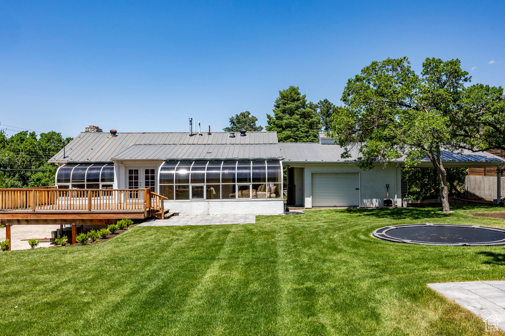 Back of house with a sunroom, a lawn, and a wooden deck