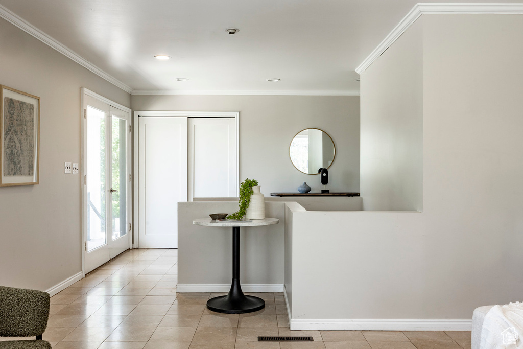 Tiled entrance foyer with a healthy amount of sunlight and crown molding