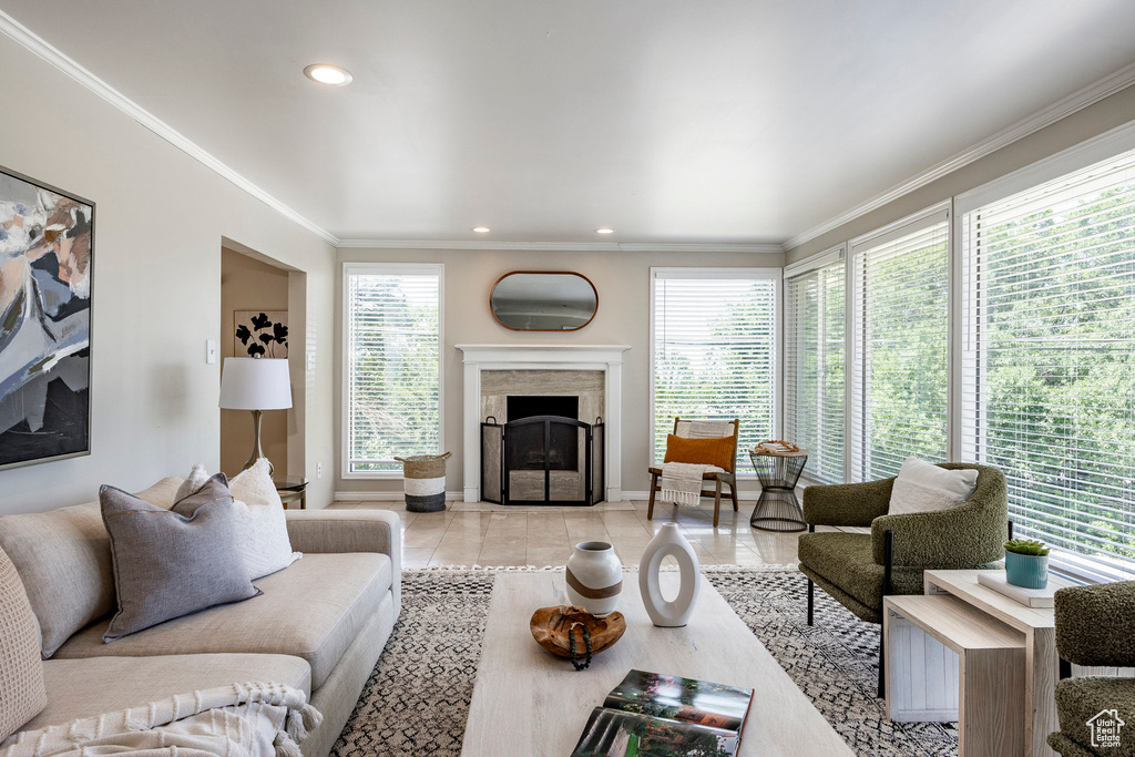 Living room with a premium fireplace, ornamental molding, and light tile flooring