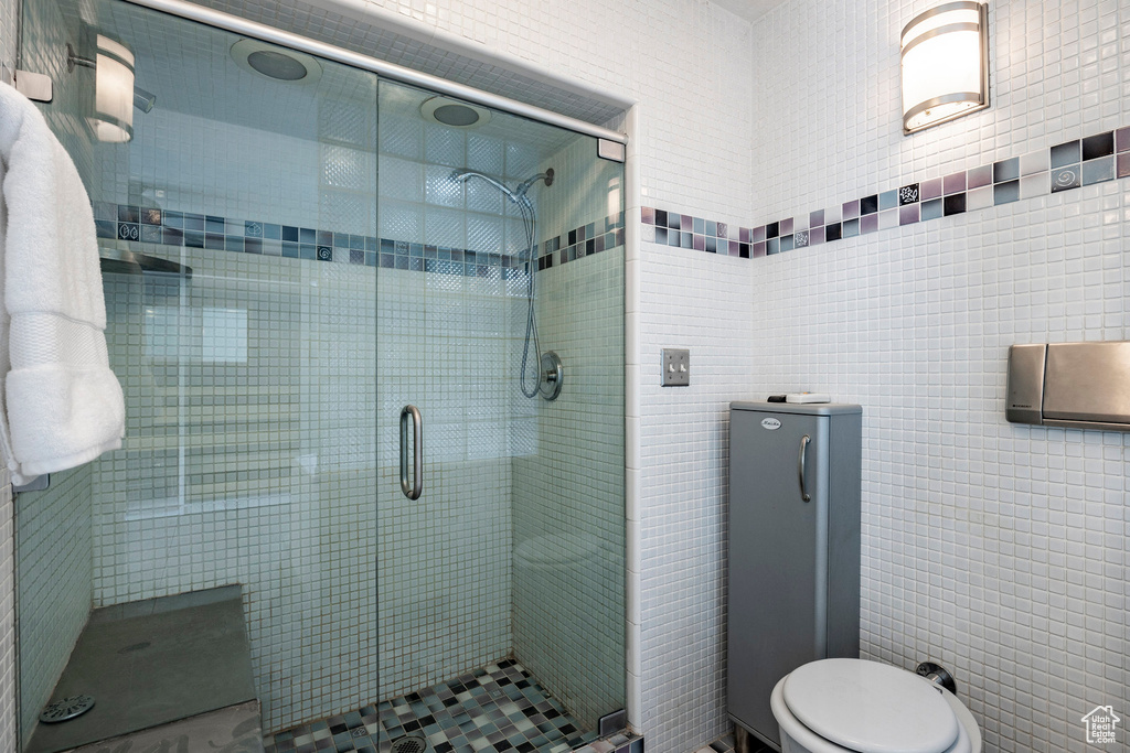 Bathroom with tile walls, an enclosed shower, and toilet