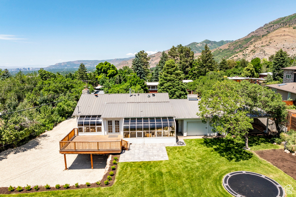 Exterior space featuring a deck with mountain view, a sunroom, and a lawn