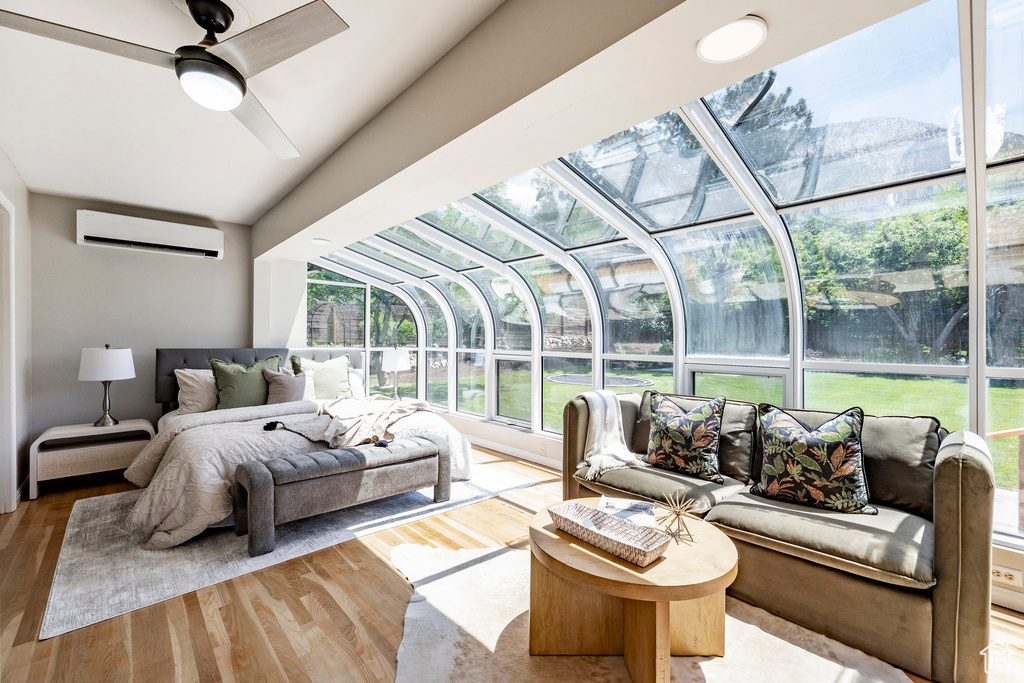 Bedroom with hardwood / wood-style flooring, ceiling fan, and a wall mounted air conditioner