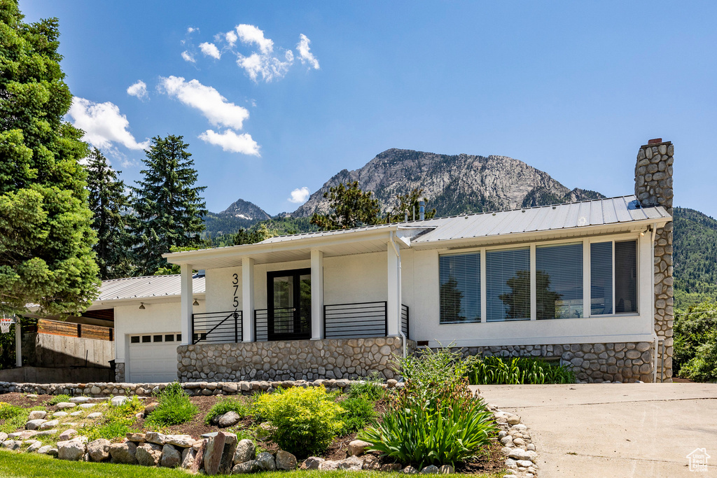 View of front facade featuring a garage, a mountain view, and covered porch