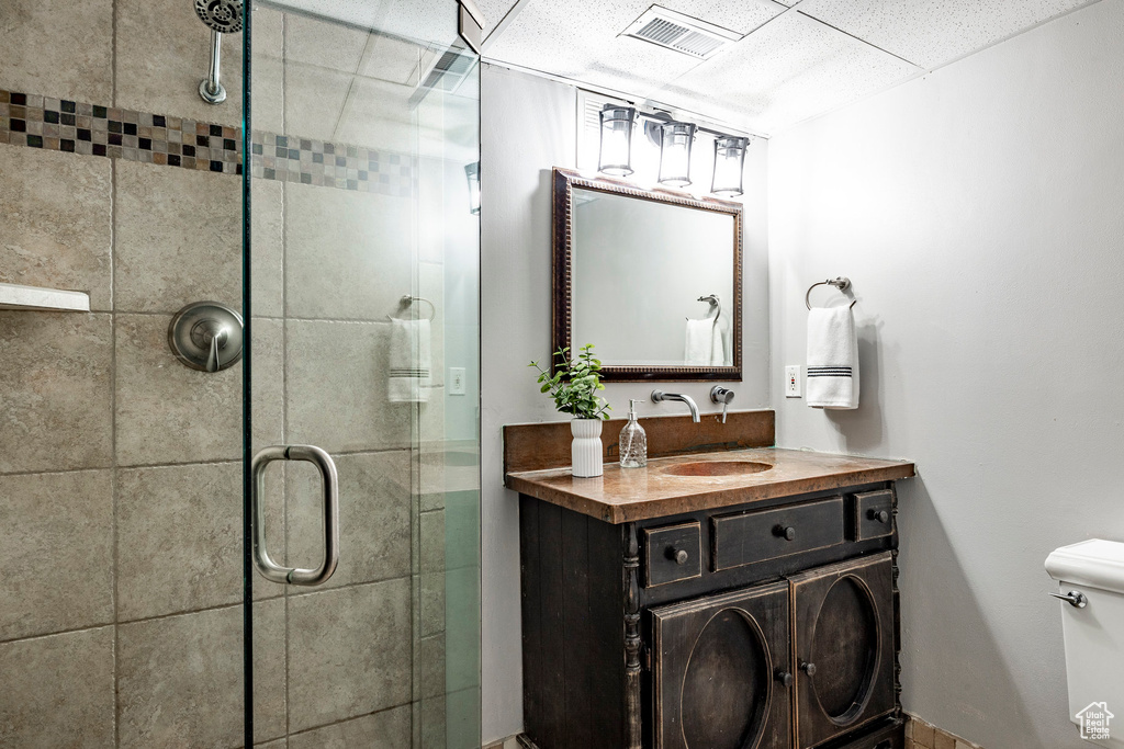 Bathroom with a shower with door, oversized vanity, and toilet