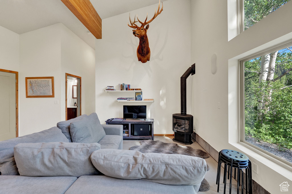 Living room featuring a high ceiling, beam ceiling, and a wood stove