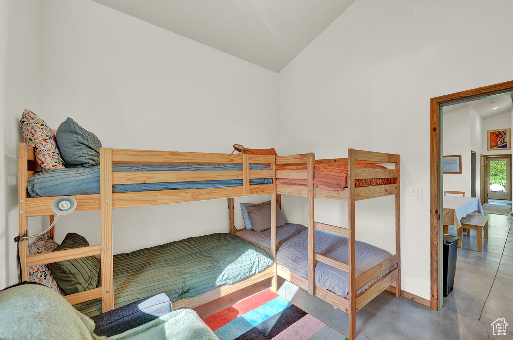 Bedroom with high vaulted ceiling and concrete floors