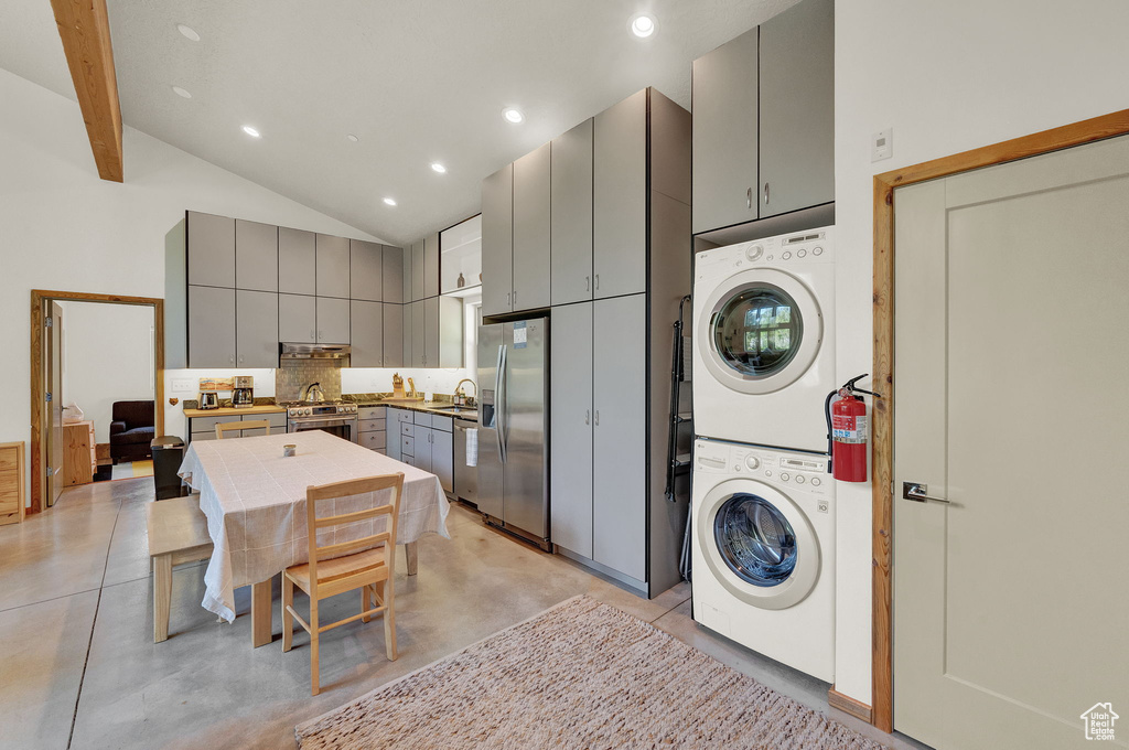 Laundry area featuring a towering ceiling, stacked washer and clothes dryer, and sink