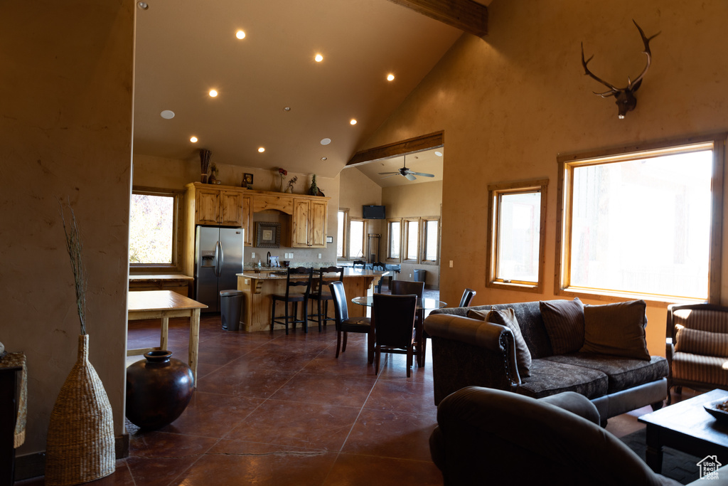 Living room featuring high vaulted ceiling, beam ceiling, dark tile flooring, and ceiling fan