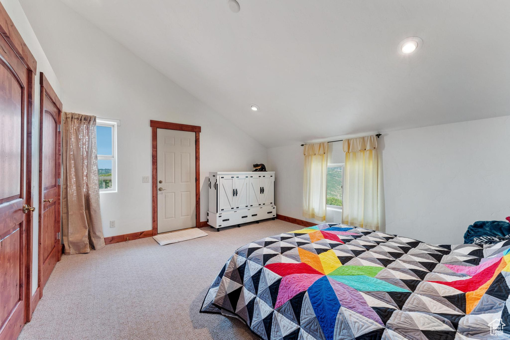 Bedroom with light carpet, multiple windows, and vaulted ceiling