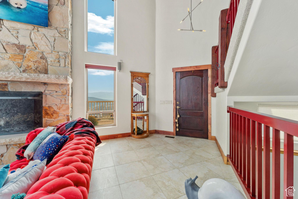 Foyer entrance with light tile patterned floors, a high ceiling, and a stone fireplace