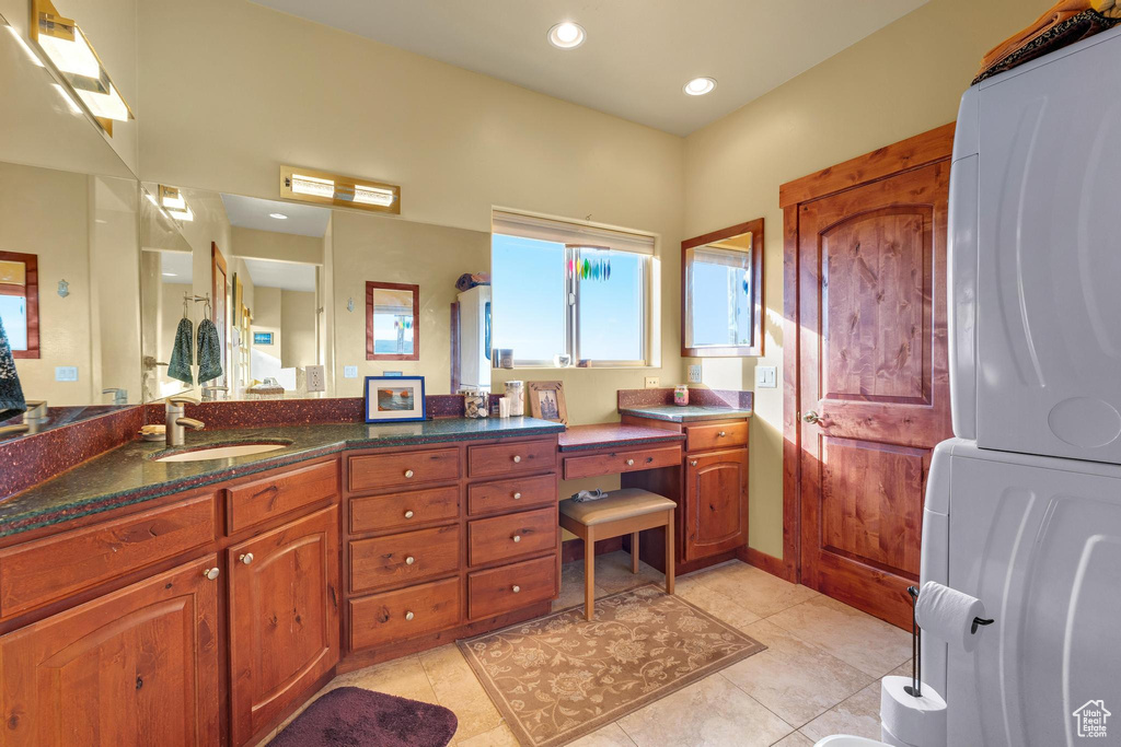 Bathroom with tile flooring, vanity, and stacked washer and dryer