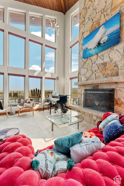 Living room with tile patterned floors, a stone fireplace, high vaulted ceiling, and wooden ceiling