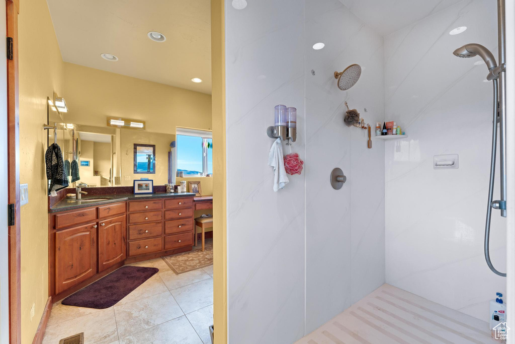 Bathroom featuring tiled shower, tile floors, and vanity